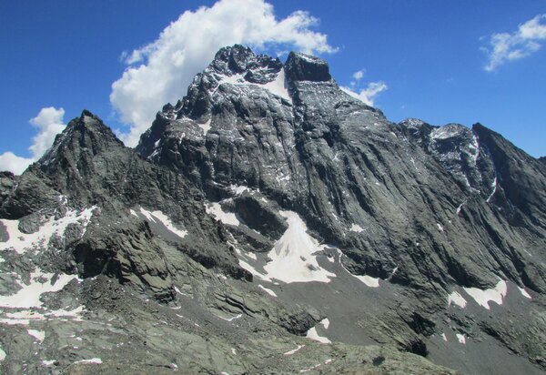 Il Monviso dalla Losetta, con in evidenza il dado di vallanta, punta squadrata sulla destra. alla base del monviso ancora alcuni nevai. nuvole sulla cima del monviso, cielo azzurro