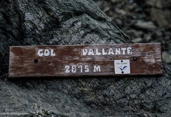 pannello in legno con la scritta Col Vallante in bianco su una roccia