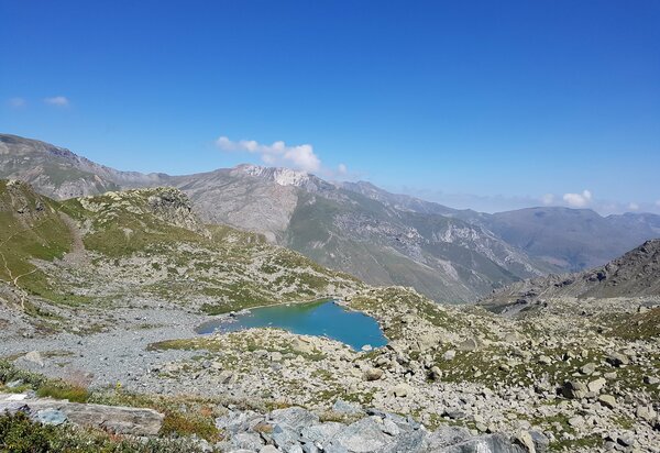 Lago da tipico colore turchese tra le rocce e le praterie alpine. cielo azzurro